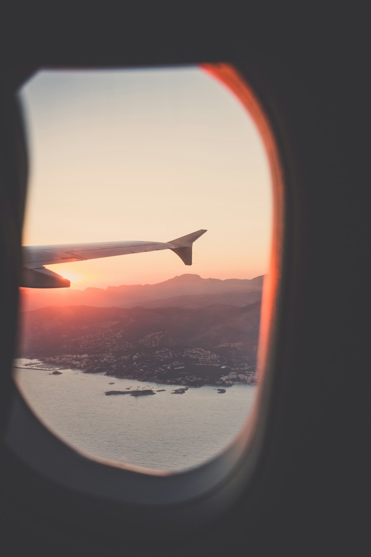 Airplane wing above clouds at sunset — international travel to China
