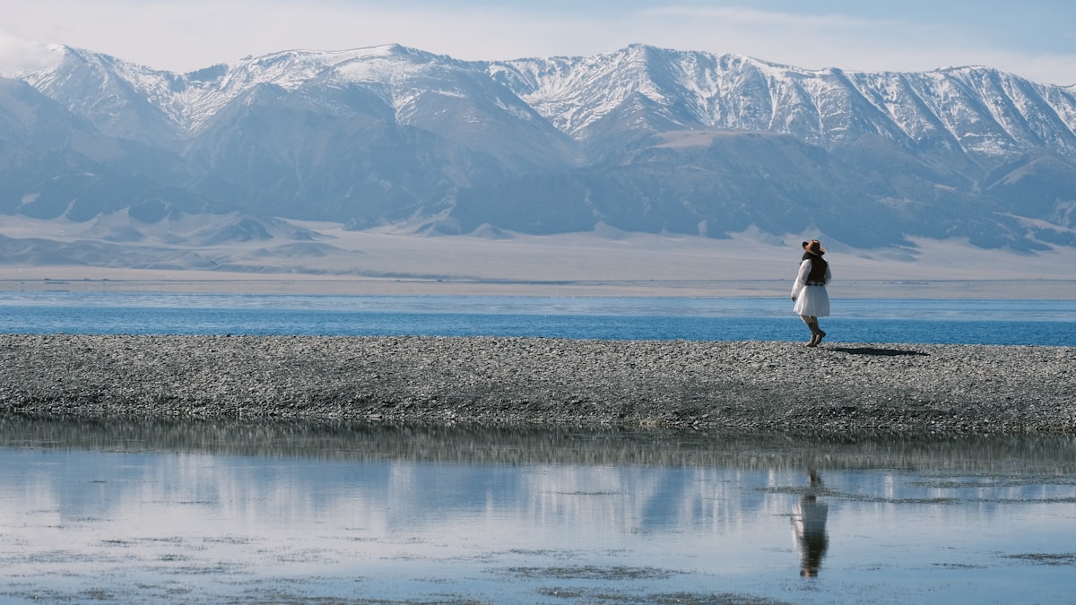 Sayram Lake in Xinjiang — brilliant turquoise water ringed by Tianshan snow peaks and wildflower meadows, the "last tear of the Atlantic"